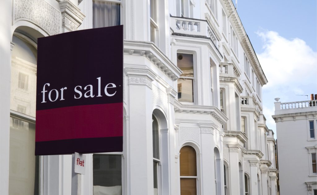 for sale sign over white home facades